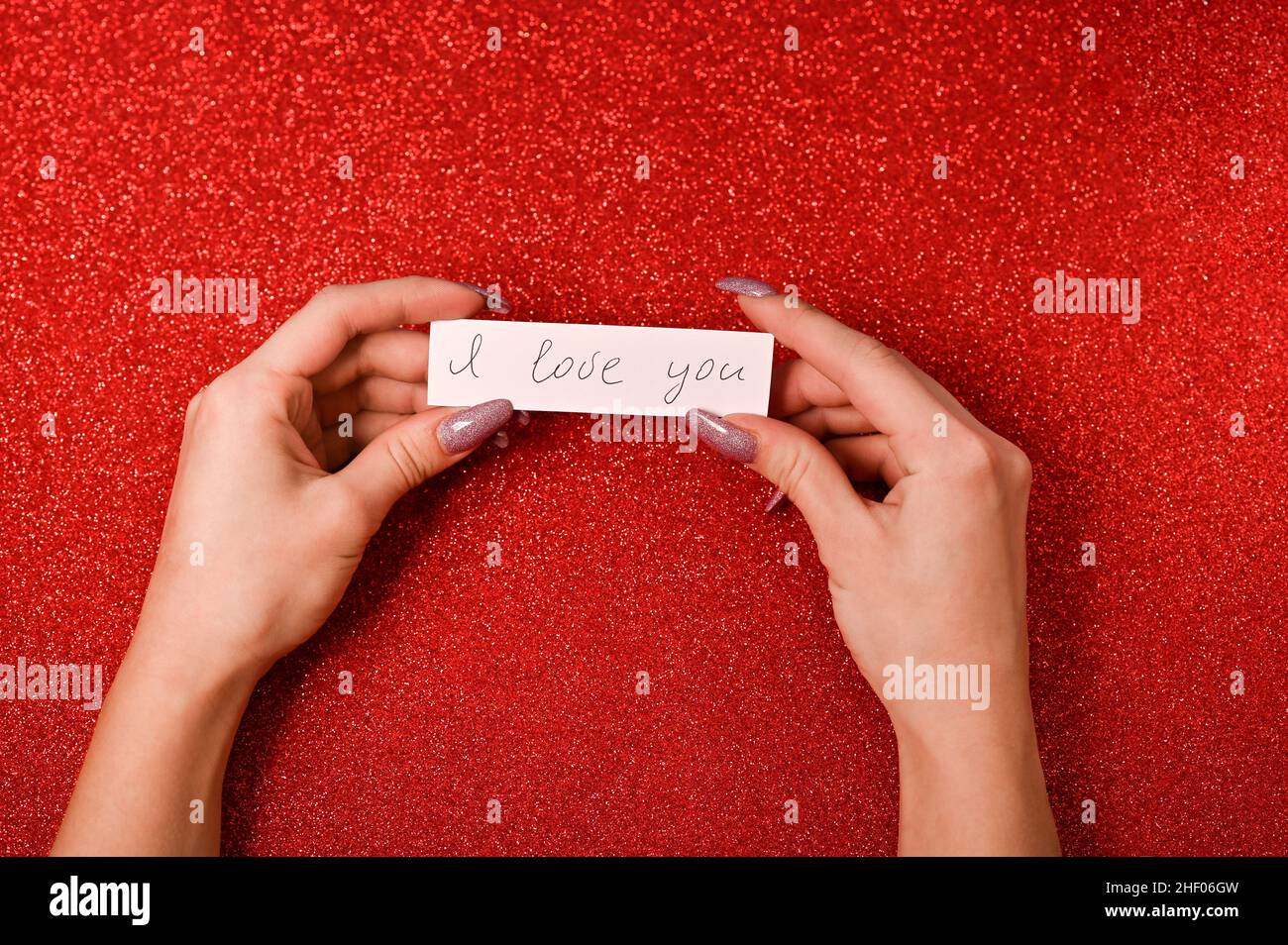 Frauenhände halten eine Notiz mit dem Text - Ich liebe dich. Stockfoto