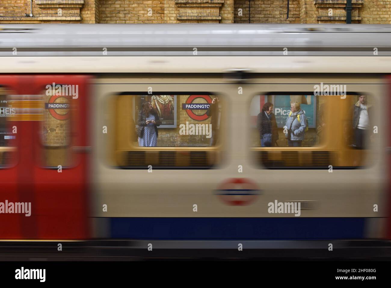 U-Bahn-Station Paddington - District und Circle Line, vorbei an Zug und Passagieren am Bahnsteig in London, Großbritannien. Stockfoto