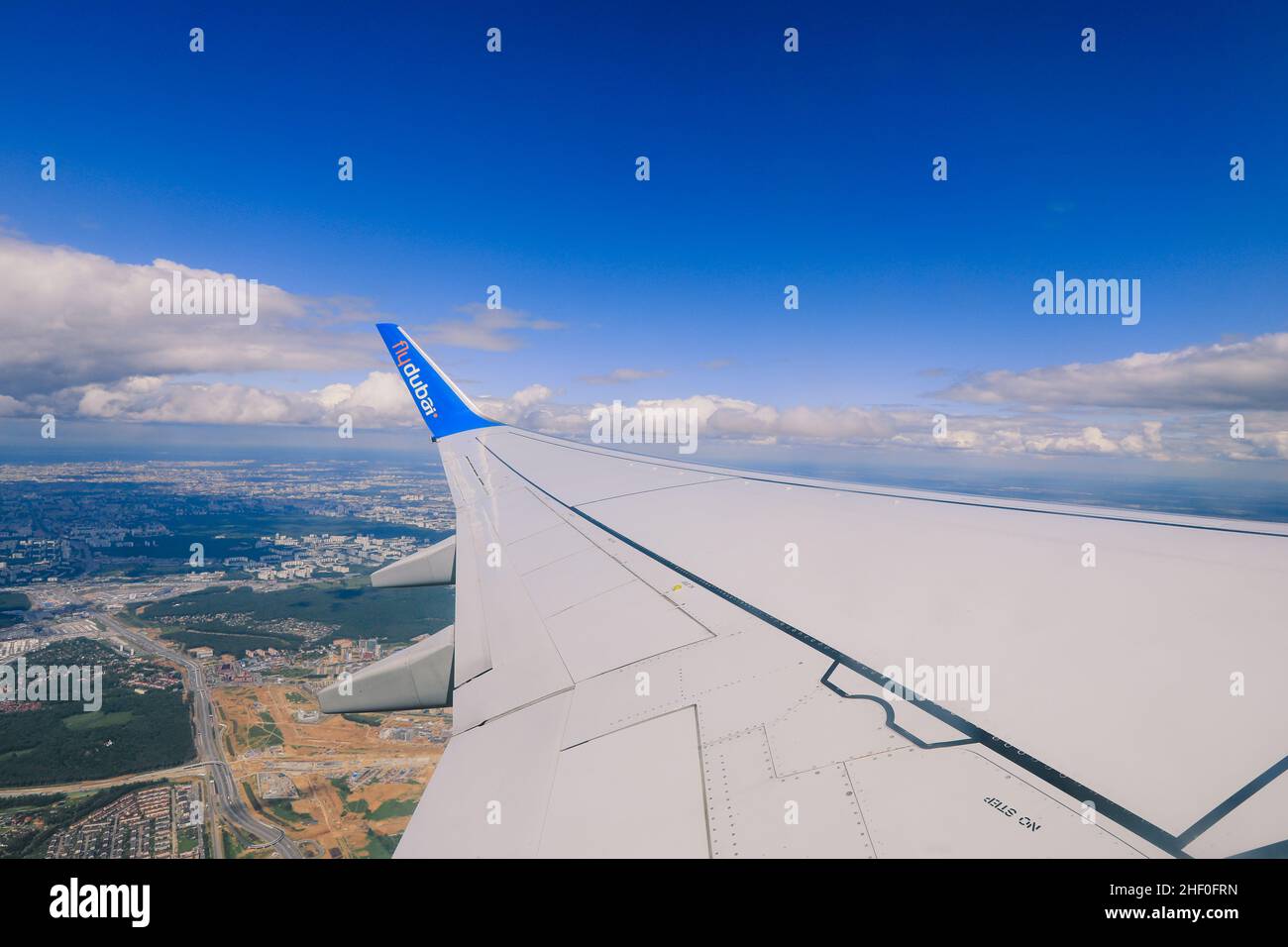 Dubai, Vereinigte Arabische Emirate - 10. Juni 2021: Fensteransicht zum Flugzeugflügel und wolkiger blauer Himmel Stockfoto