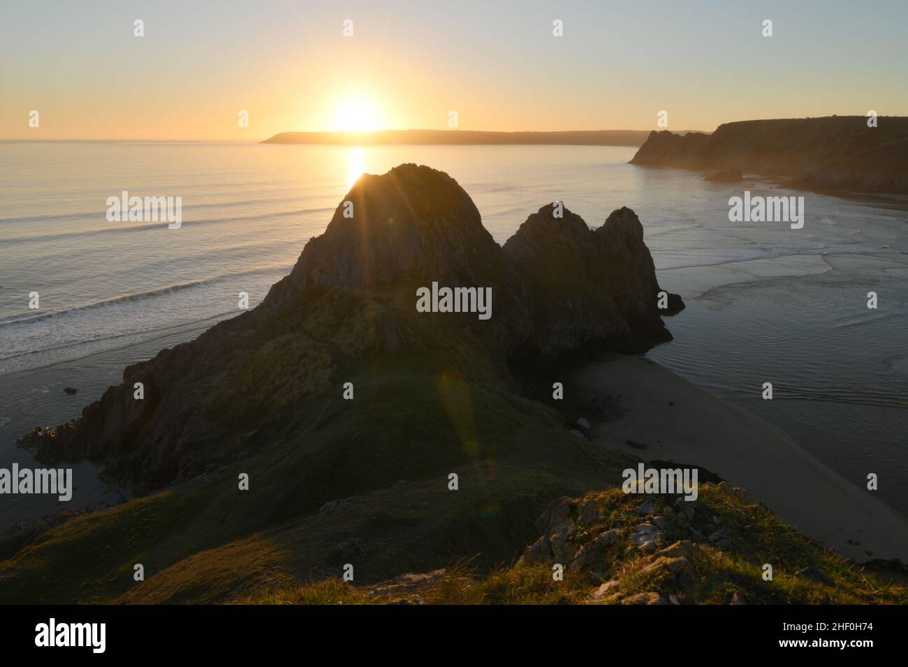 Three Cliffs Bay mit Sonnenuntergang hinter Oxwich Point in Südwales Stockfoto