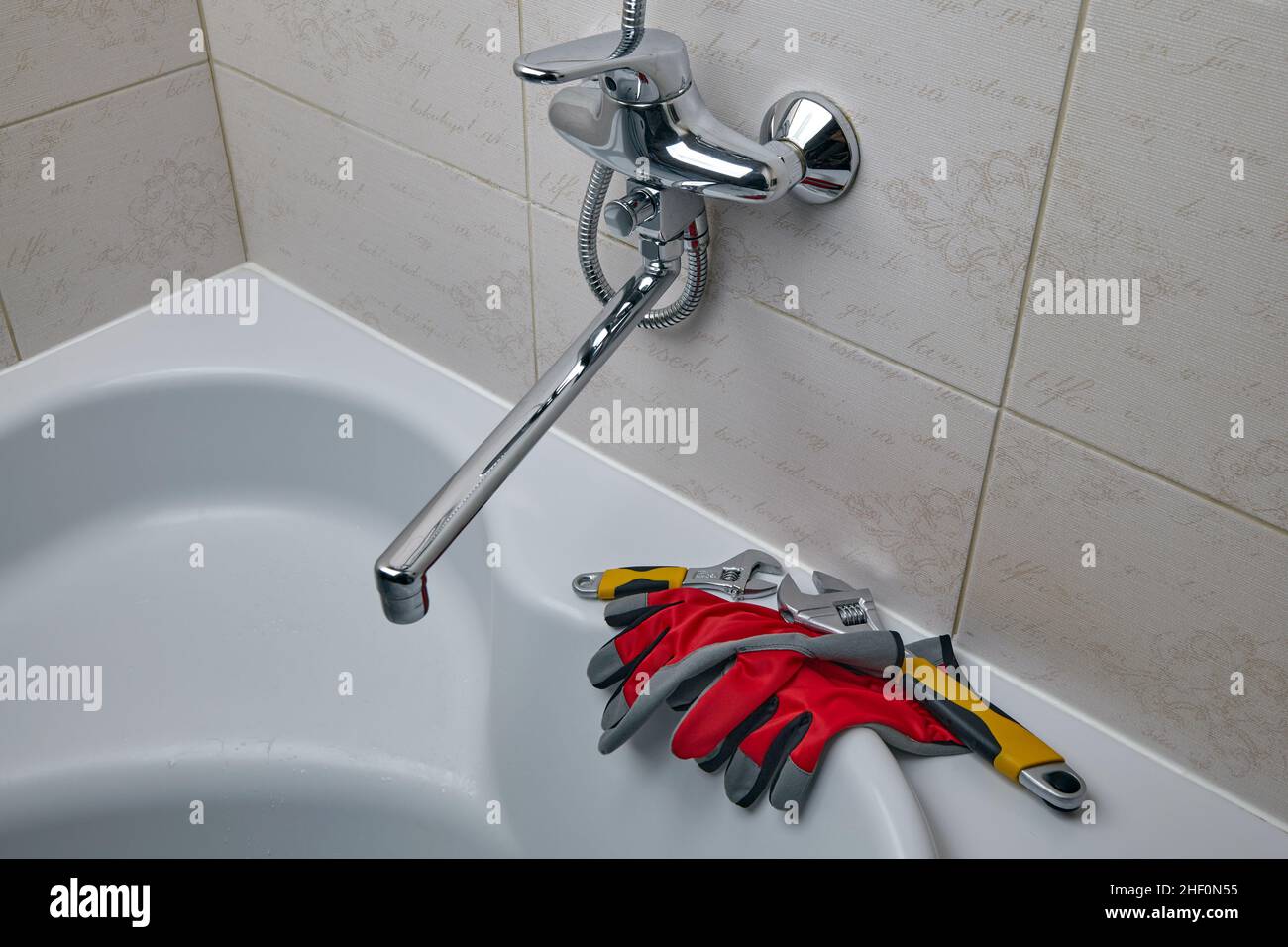 Verstellbare Klempnerschlüssel und Klempnerhandschuhe in der Dusche Stockfoto