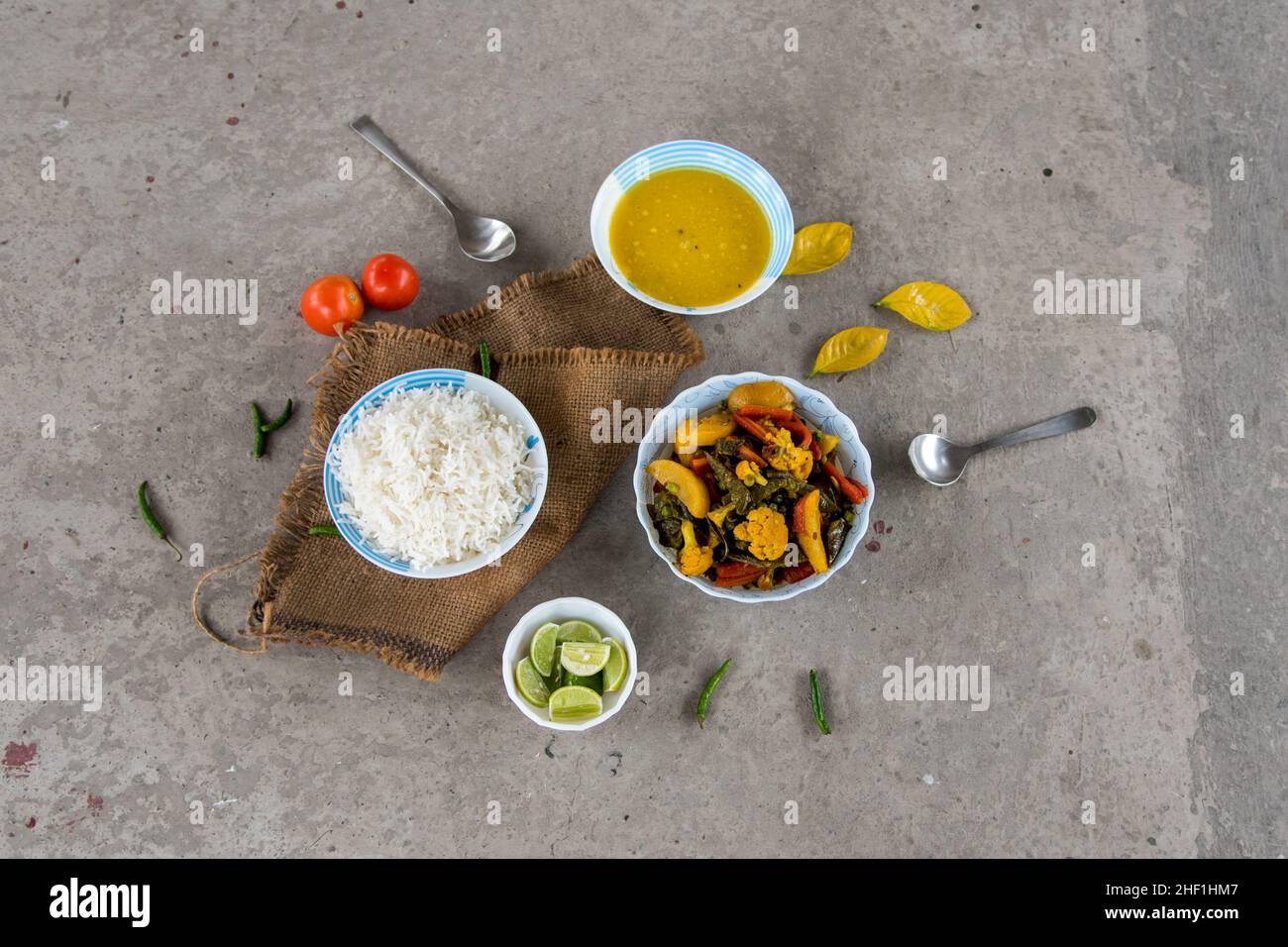 Indisches Mittagsmenü gemischtes Gemüse, gedämpfter Reis und gelbes Dal oder Hülsenfrüchte, serviert in Schüsseln zusammen mit Gewürzen. Draufsicht. Stockfoto
