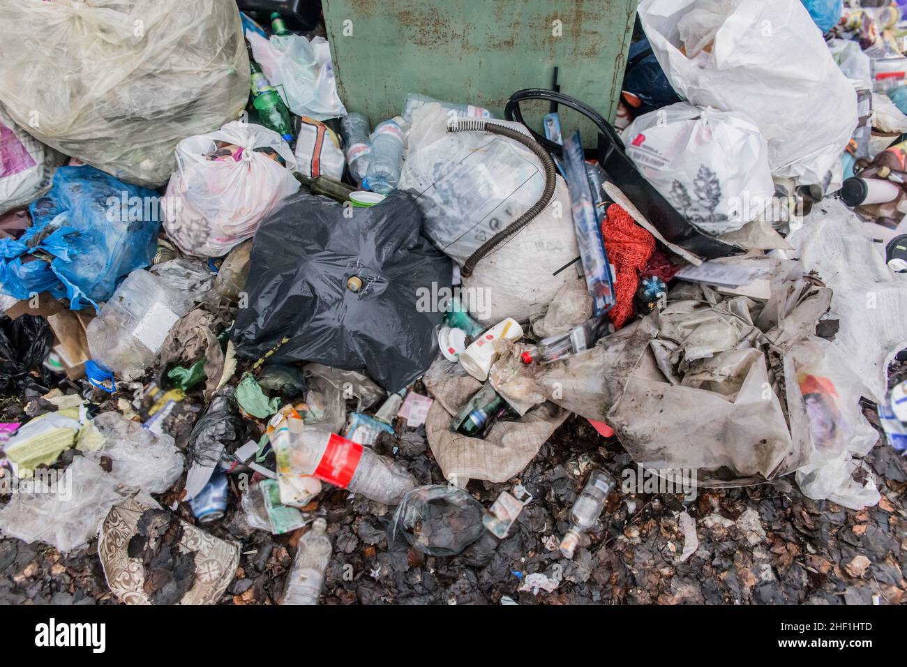 Abfall Glas- und Plastikflaschen und -Beutel am Behälter mit Abfall im Freien. Stockfoto