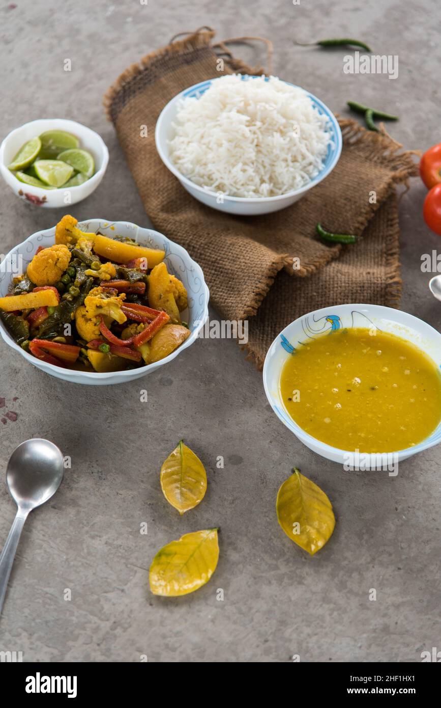 Indisches Mittagsmenü gemischtes Gemüse, gedämpfter Reis und gelbes Dal oder Hülsenfrüchte, serviert in Schüsseln zusammen mit Gewürzen. Draufsicht. Stockfoto
