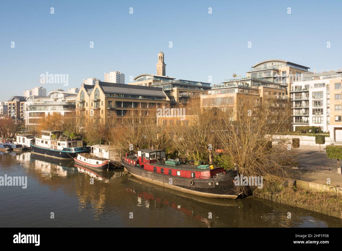 Hausboote auf der Themse mit der neuen Wohnanlage Kew Bridge Road im Vordergrund und der Wohnanlage Brentford Towers im Hintergrund Stockfoto