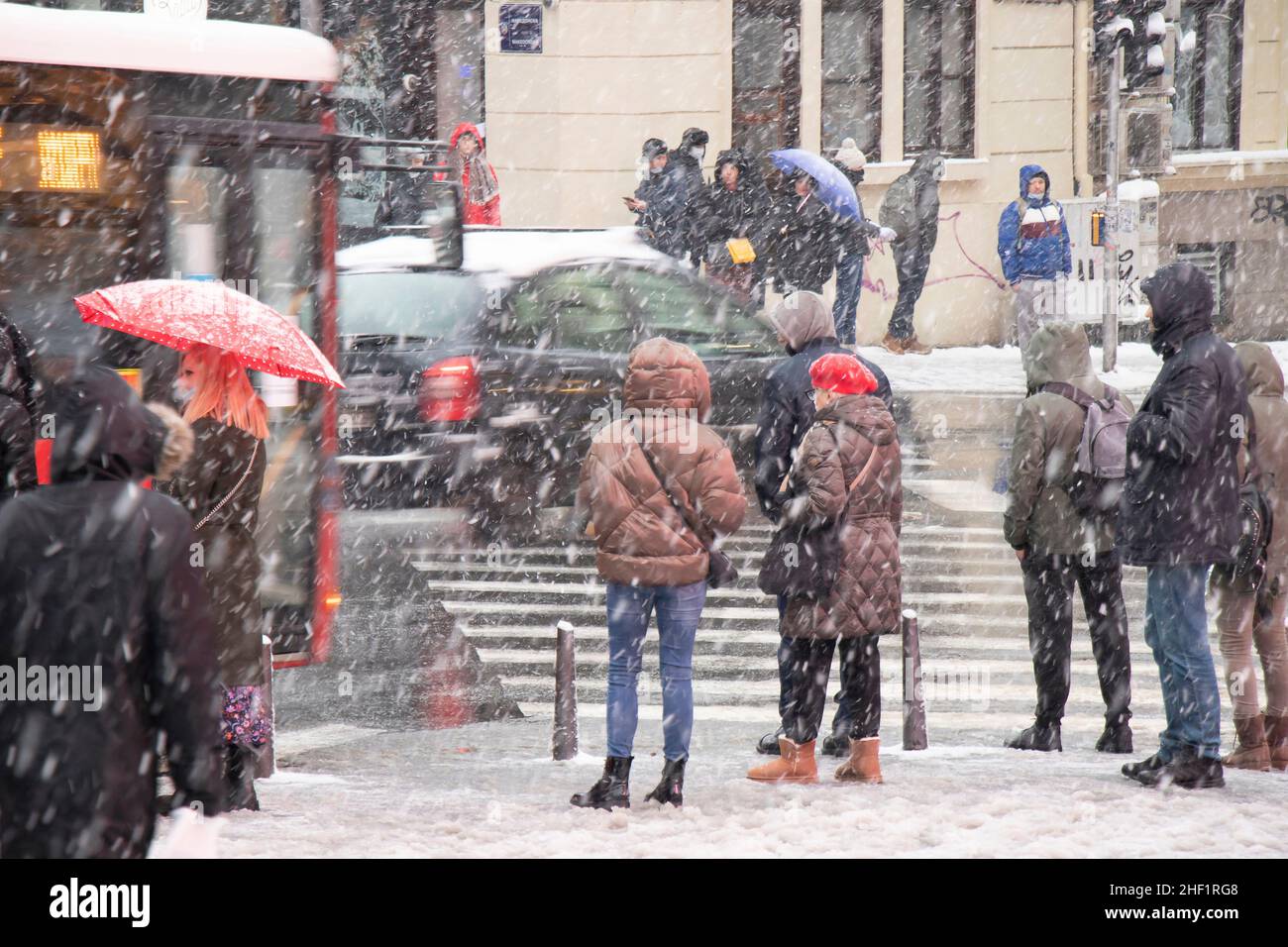 Belgrad, Serbien - 11. Januar 2022: Menschen warten an einer Kreuzung auf einer verschneiten Stadtstraße während eines starken Schneefalls Stockfoto