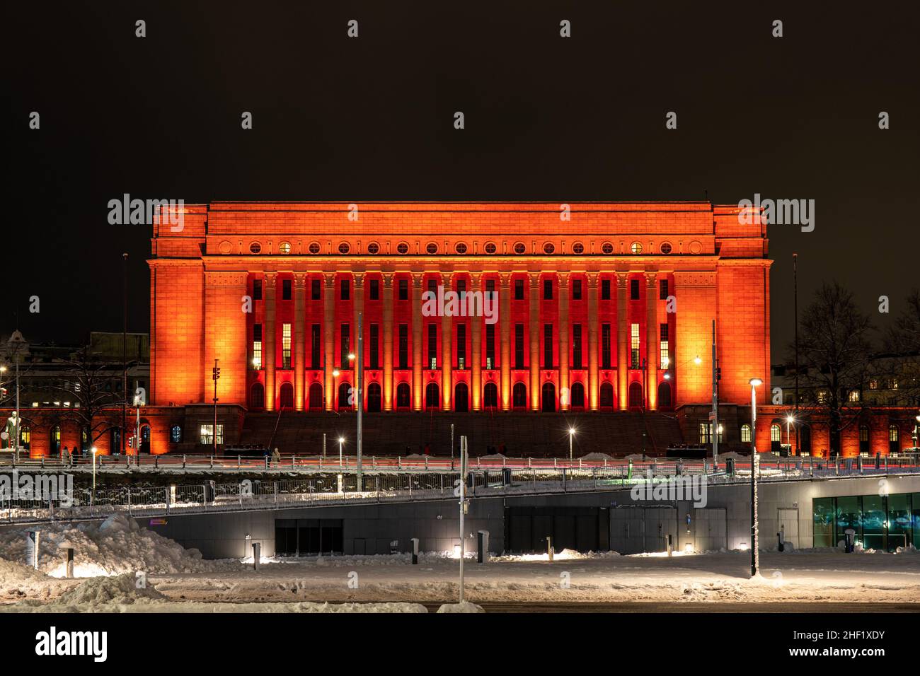 Das Parlamentsgebäude wurde während des Lux Helsinki Light Art Festivals in Helsinki, Finnland, rot oder orange beleuchtet Stockfoto