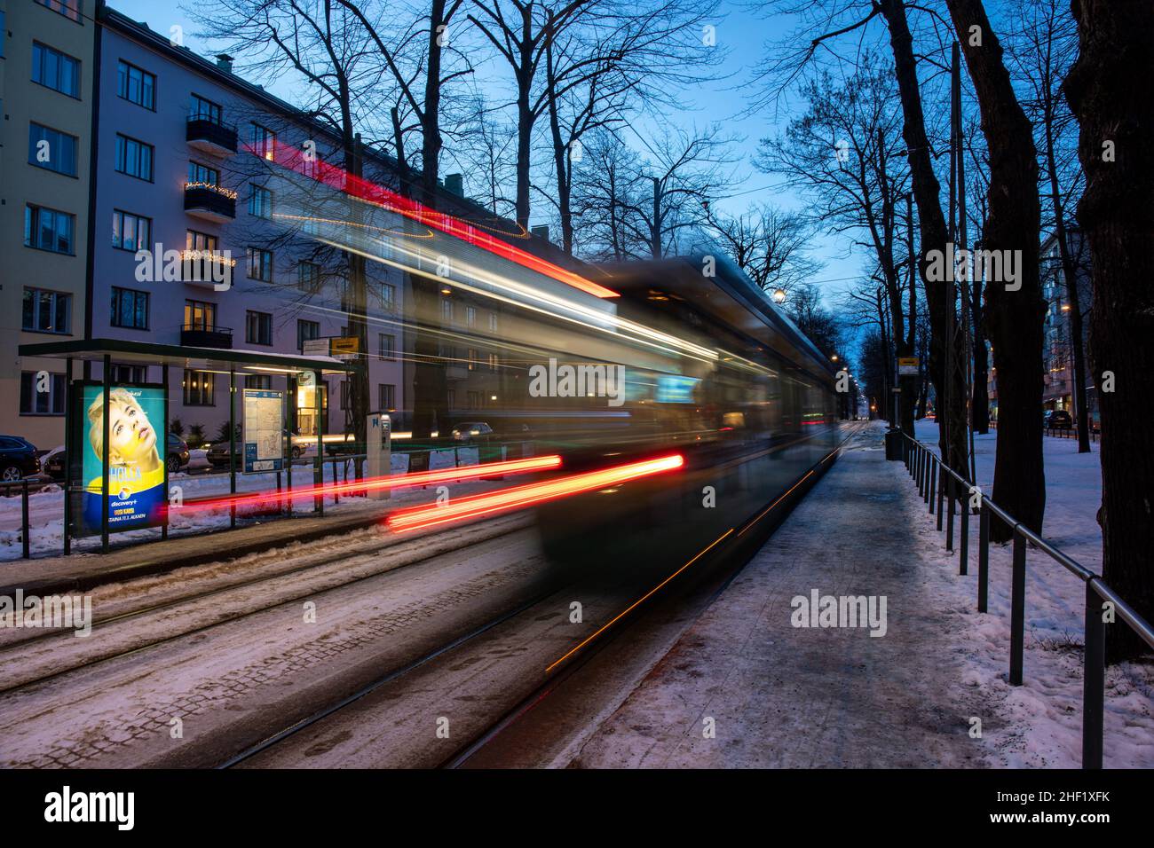 Langzeitbelichtung verwackelte Bewegungsaufnahme der Straßenbahn der Linie 4 in der Abenddämmerung im finnischen Munkkiniemi-Viertel Stockfoto