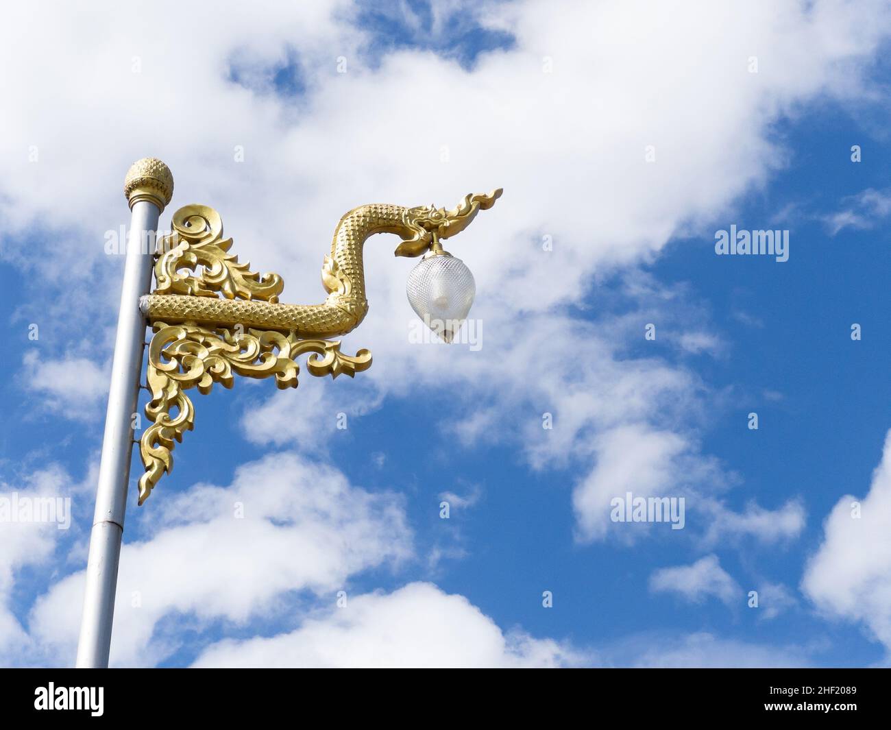 Die goldene Schlangenstatue wurde an einem Straßenlichtmast im thailändischen Tempel geschmückt, Vorderansicht mit dem Kopierraum. Stockfoto