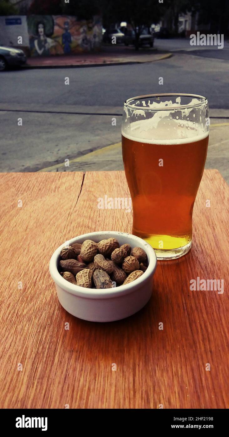 Rotes Craft-Bier mit Erdnüssen auf Holztisch Stockfoto