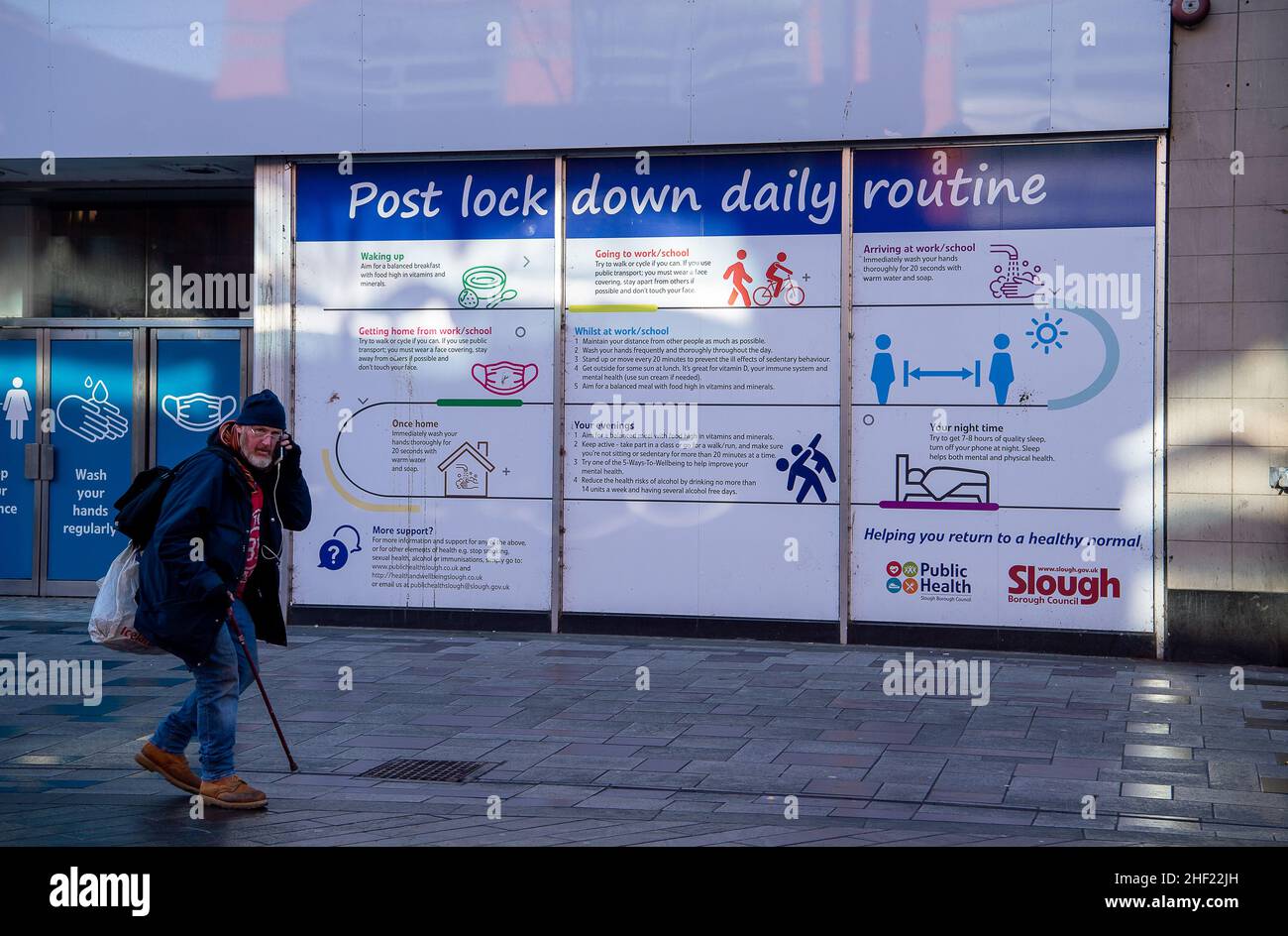 Slough, berkshire, Großbritannien. 13th. Januar 2022. Ein Mann geht an Post Covid-19 vorbei, die täglich routinemäßige Banner in der Slough High Street einsperren. Quelle: Maureen McLean/Alamy Stockfoto