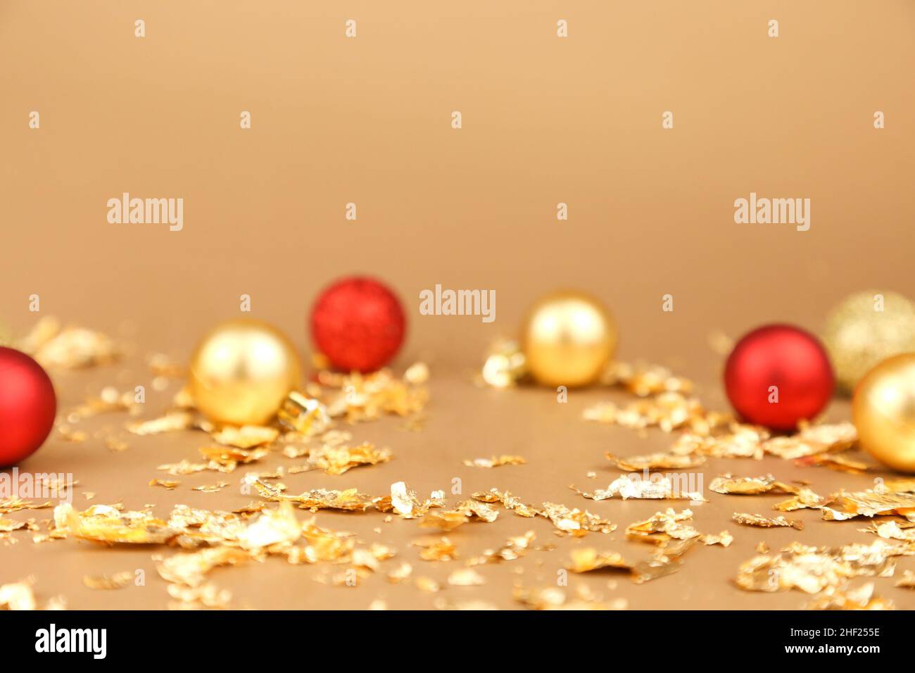 Hintergrund der Werbung für Kosmetikprodukte. Rote und goldene weihnachtskugeln und goldene Papierfeuerungen auf goldenem Hintergrund. Leerer Ort zum Anzeigen Stockfoto