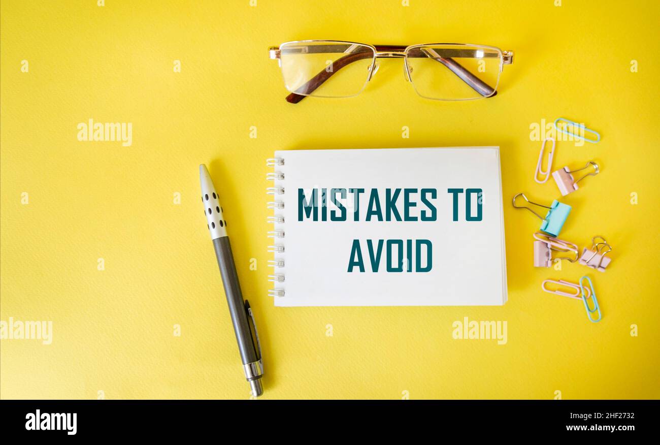 Notizblock mit zu vermeidende Textfehler, mit Büroklammern und einem Stift und einer Brille auf gelbem Hintergrund. Kann als Konzeptfoto verwendet werden Stockfoto