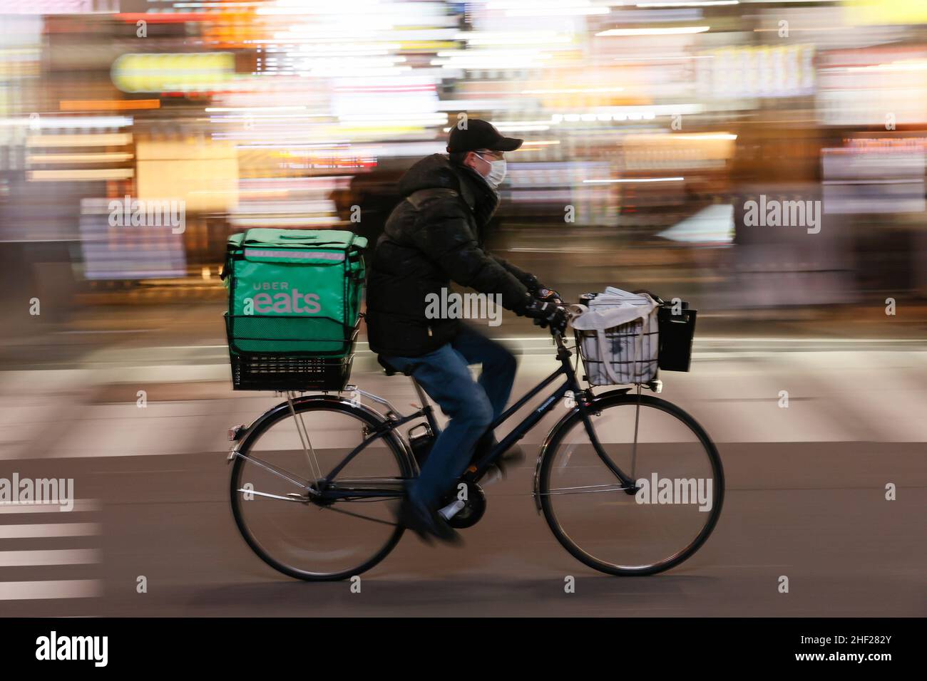 Tokio, Japan. 13th Januar 2022. Ein Uber isst einen Mann mit einer Schutzmaske, um die Ausbreitung des Coronavirus zu verhindern, der an Kabukicho, dem Unterhaltungs- und Rotlichtviertel auf der Shinjuku-Station, vorbeifährt. Tokio bestätigte am Donnerstag 3.124 COVID-19-Fälle, ein erstmals seit dem 2021. September höherer Rekord, inmitten der raschen Ausbreitung der omicron-Variante in der Hauptstadt. (Bild: © Rodrigo Reyes Marin/ZUMA Press Wire) Stockfoto