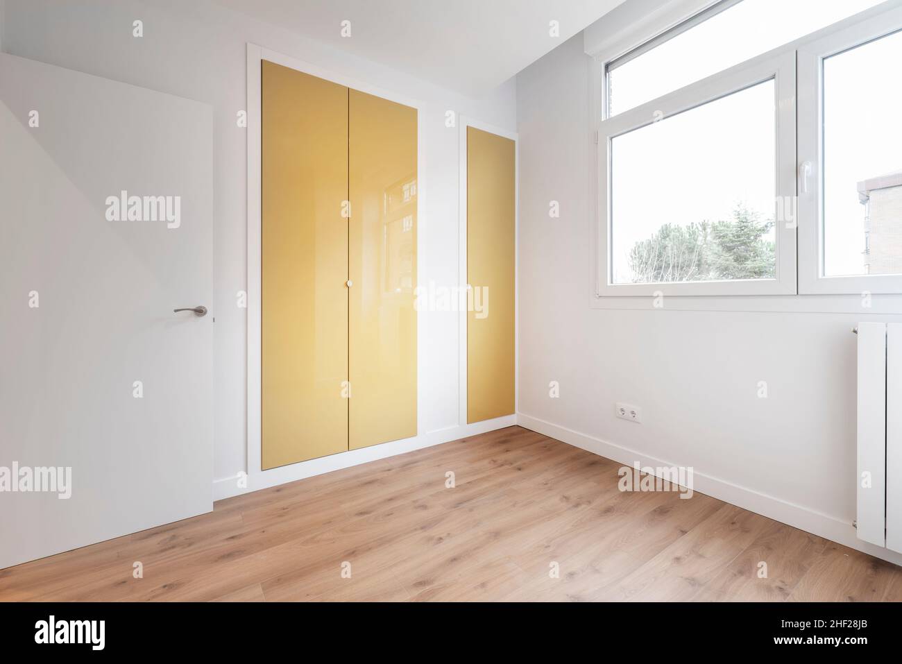 Schlafzimmer mit Einbauschrank mit senffgelb lackierten Türen Stockfoto