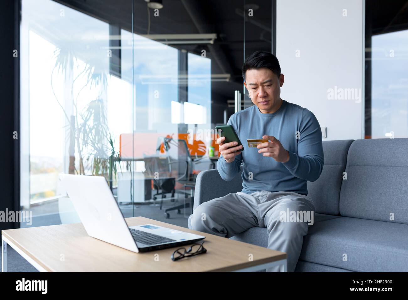 Ängstlich asiatische versuchen, Online-Zahlung per Kreditkarte und Telefon, Geschäftsmann arbeiten im Büro, Bank-Antrag Fehler zu machen Stockfoto