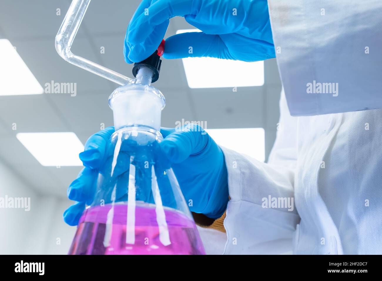 Nahaufnahme Wissenschaftler verwendet eine Titrationsmethode der Analyse, um die chemischen Eigenschaften der Wasserprobe zu studieren. Wissenschaftler, der Erlenmeyerkolben mit rosa Lösung hält Stockfoto