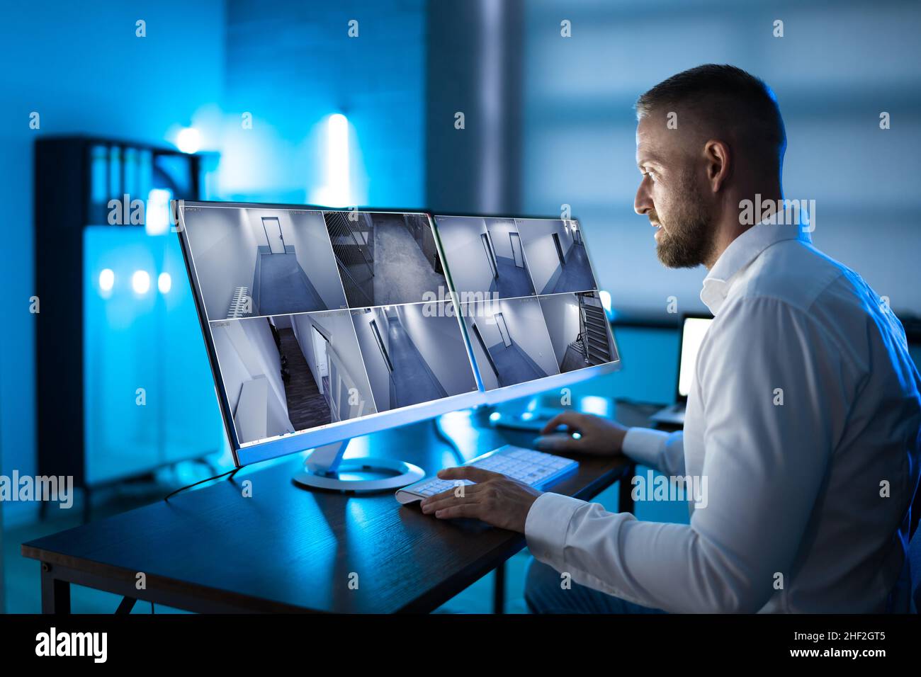 Der Bediener des Sicherheitssystems sieht sich CCTV-Aufnahmen am Schreibtisch an Büro Stockfoto