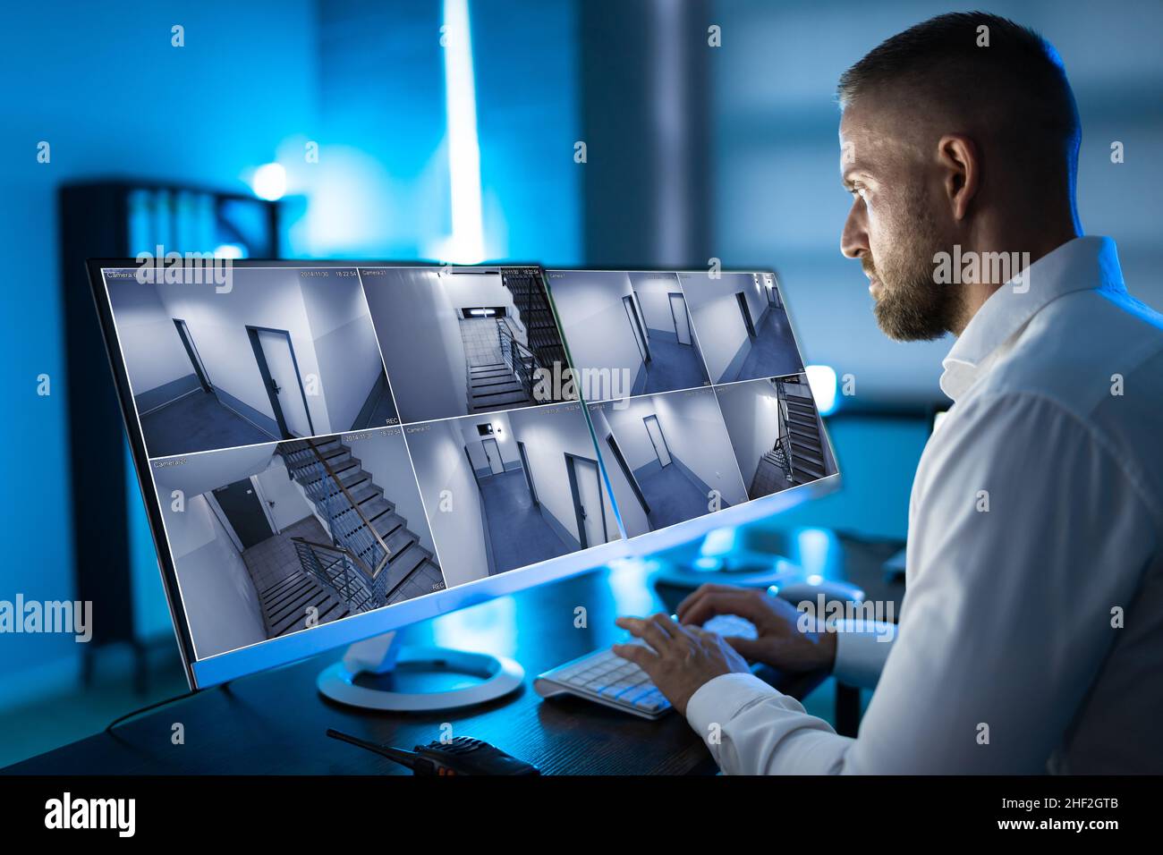 Der Bediener des Sicherheitssystems sieht sich CCTV-Aufnahmen am Schreibtisch an Büro Stockfoto