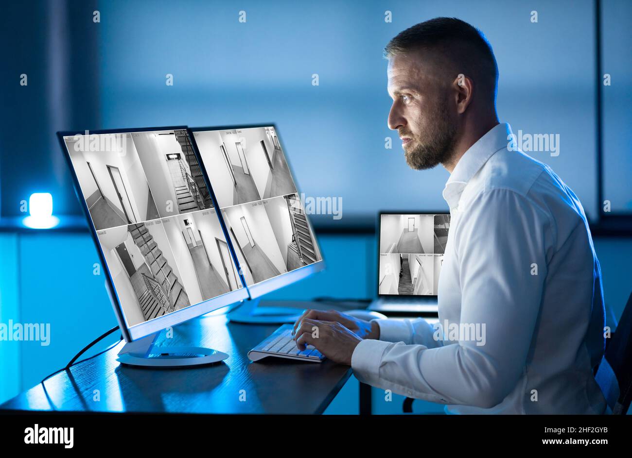 Der Bediener des Sicherheitssystems sieht sich CCTV-Aufnahmen am Schreibtisch an Büro Stockfoto