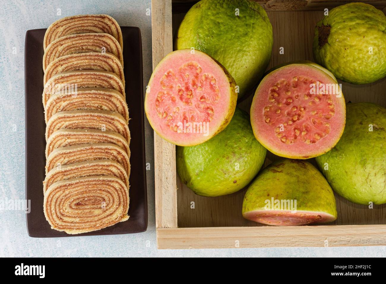Geschnittener Bolo de rolo (Rollkuchen) neben einer Schachtel mit guavas top-Ansicht. Stockfoto