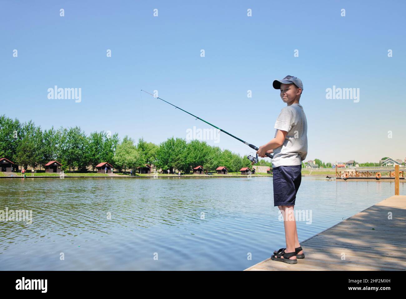 Der junge liebt es, am sonnigen Sommertag am See oder Teich zu fischen. Stockfoto