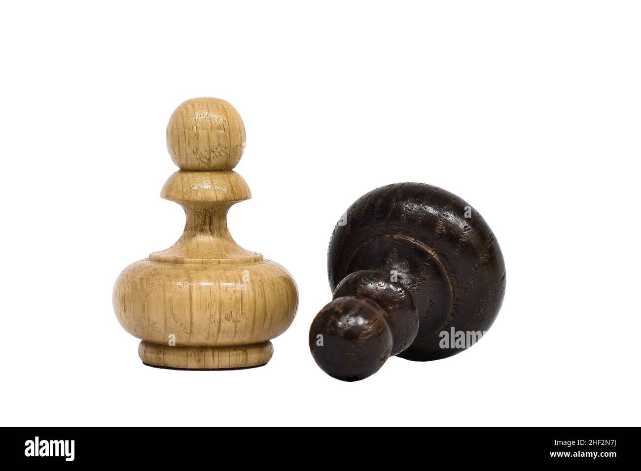 Schachfiguren isoliert auf weißem Hintergrund. Die weiße Schachfigur steht über der liegenden schwarzen Spielfigur. Sieg und Niederlage Konzept. Stockfoto