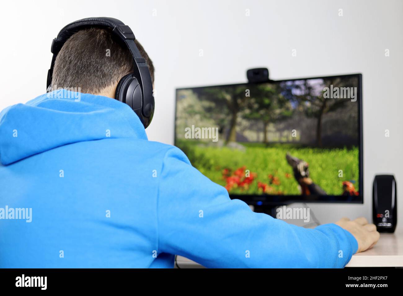 Mann mit Kopfhörern, der ein Computerspiel auf einem Desktop-PC spielt. Konzept der Spielsucht, Freizeit zu Hause Stockfoto