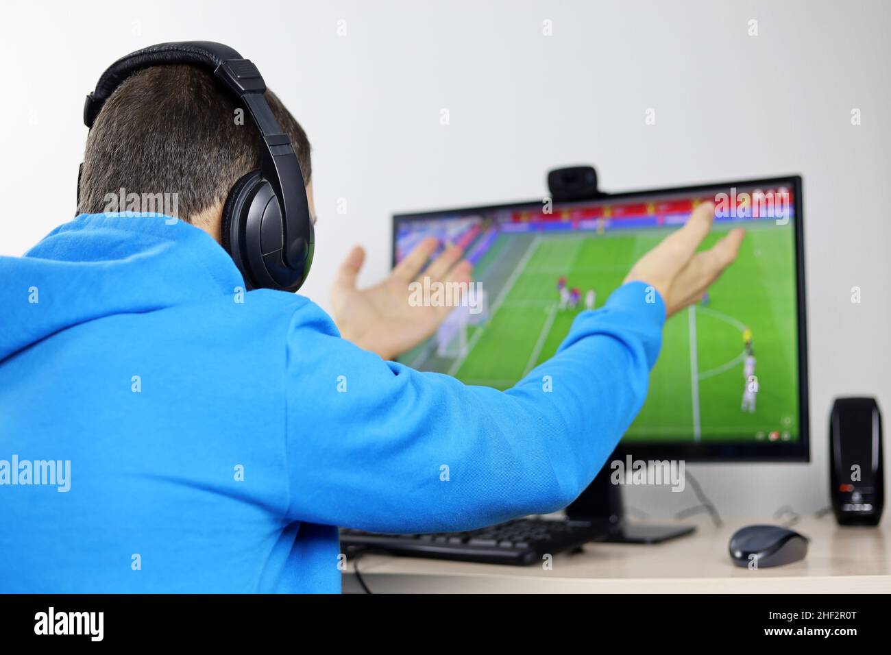 Mann, der Fußballspiel auf dem Display des Desktop-PCs ansieht. Enttäuschter oder schockierter Fan, der sich Sorgen um seine Lieblingssportmannschaft gemacht hat Stockfoto