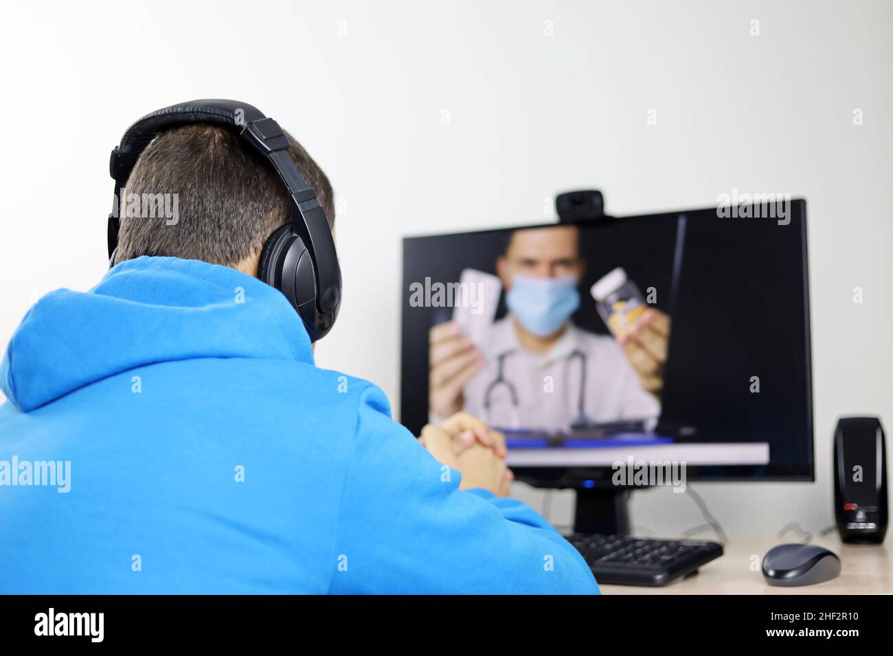 Online-Beratung mit einem Arzt, hört Mann auf die Arztempfehlungen sitzen vor der PC-Webcam. Person in Kopfhörern während des Video-Chats Stockfoto