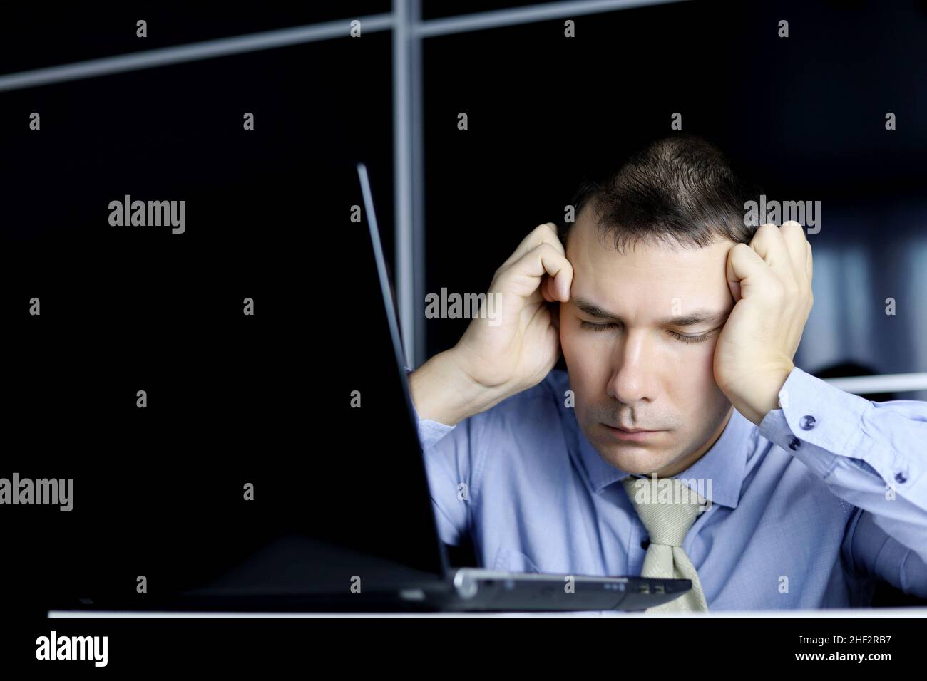 Mann in Krawatte schläft am Laptop. Büroangestellter nach schlafloser Nacht, müde von überarbeitetes Konzept, chronische Müdigkeit am Arbeitsplatz Stockfoto