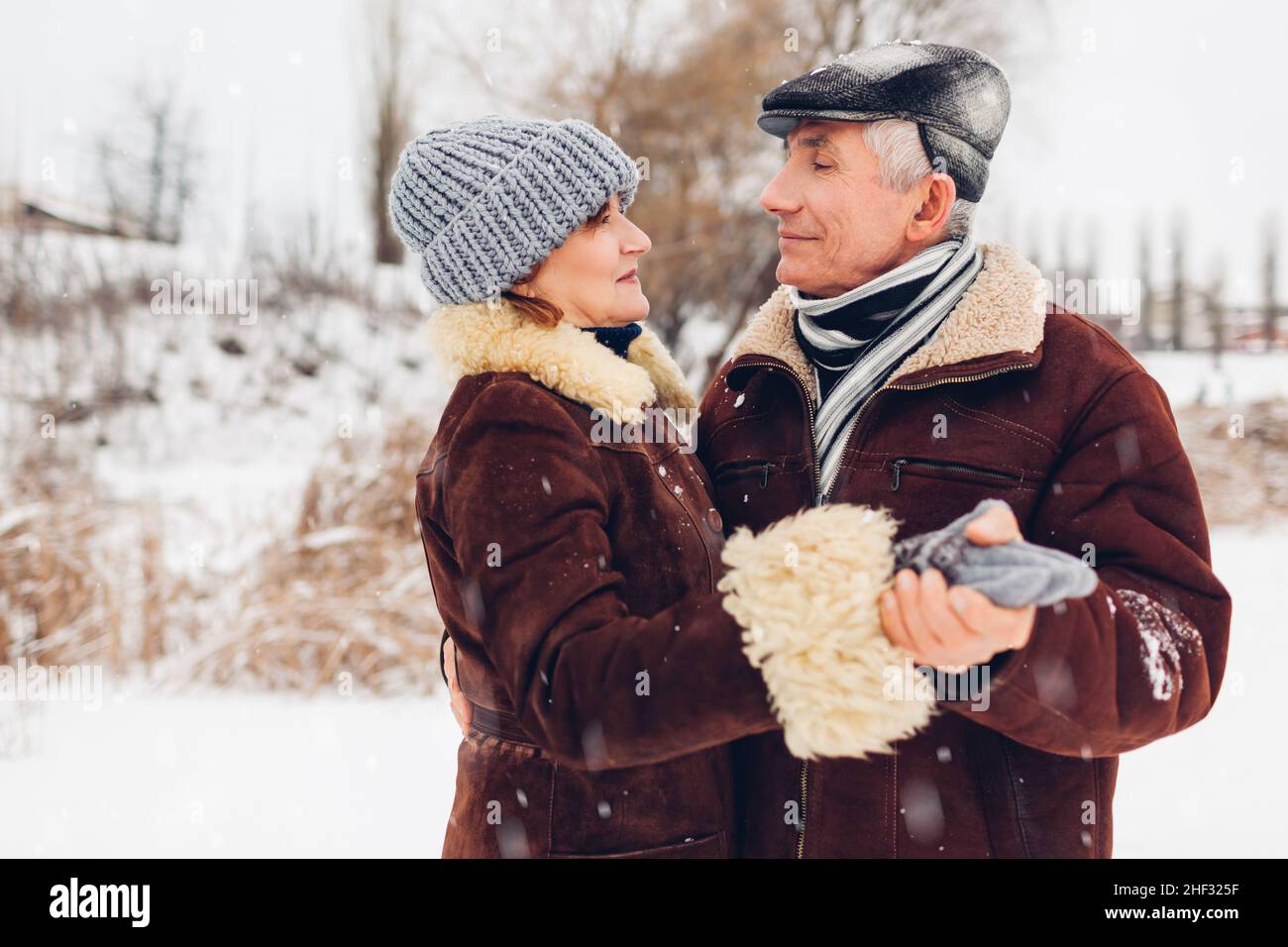 Ältere Familienpaare tanzen bei schneebedecktem Winterwetter im Freien. Ältere Menschen haben Spaß beim Gehen. Valentinstag Stockfoto