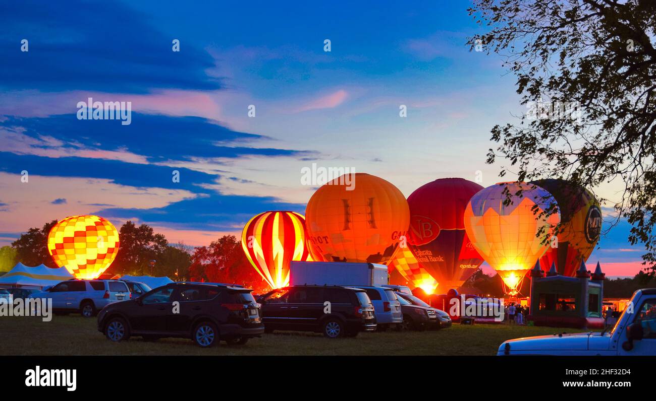 Mehrere Heißluftballons Glow as Balloons feuern dort Propan Tanks und leuchten die Ballons an einem Sommerabend auf Stockfoto