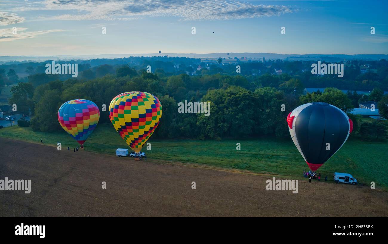 Mehrere Heißluftballons landen auf Ackerland, während die Amish-Look-On und More Still in Flight zu sehen sind Stockfoto