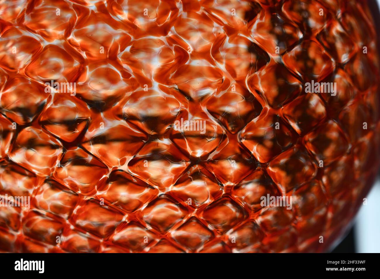Nahaufnahme der orangefarbenen Glaskugel mit Rautenmuster. Stockfoto