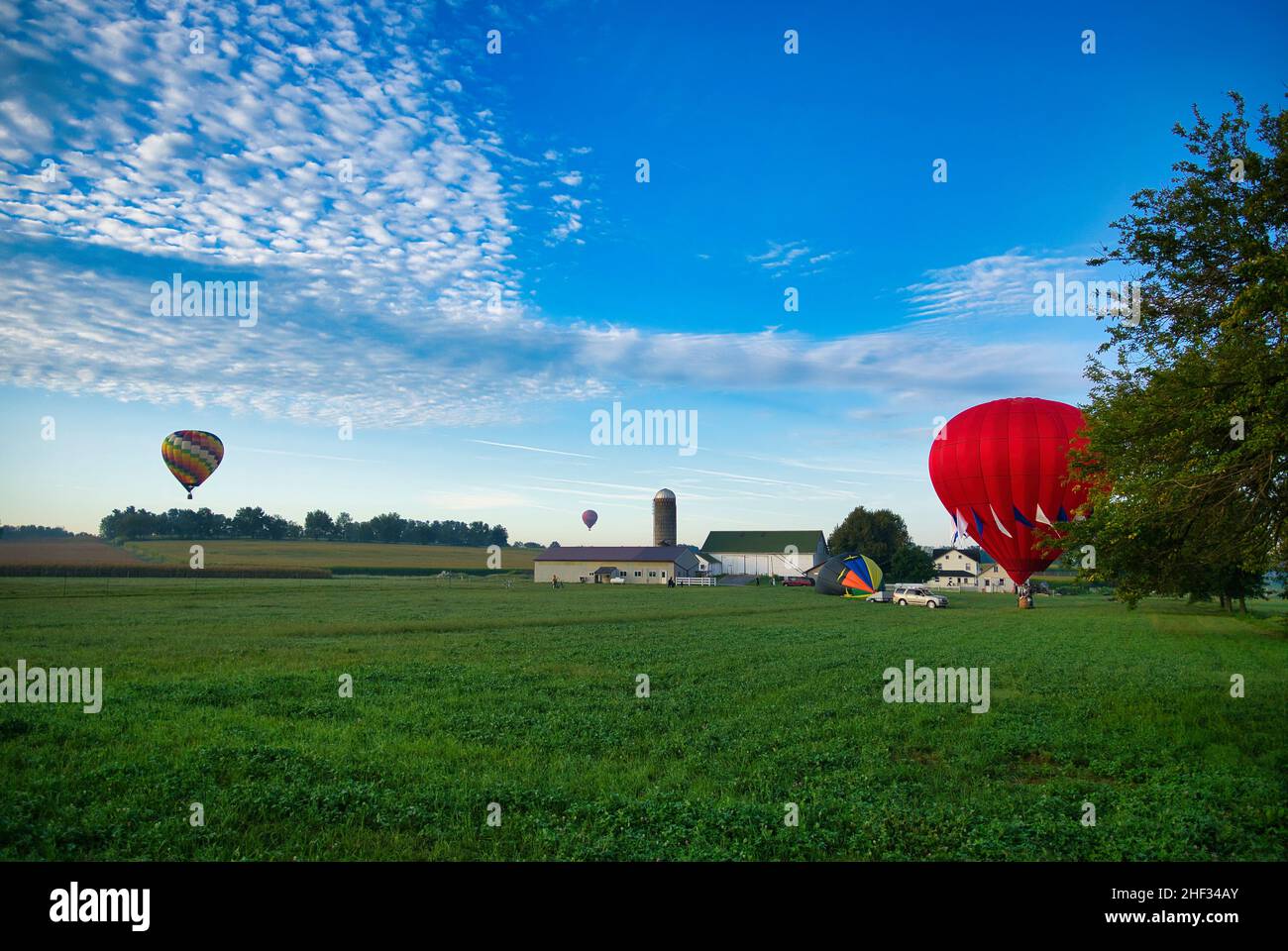 Mehrere Heißluftballons landen auf Ackerland, während die Amish-Look-On und More Still in Flight zu sehen sind Stockfoto