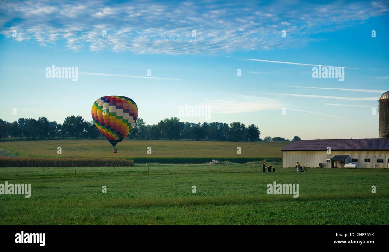 Heißluftballons landen auf Ackerland, während die Amish-Look-On und More Still in Flight zu sehen sind Stockfoto