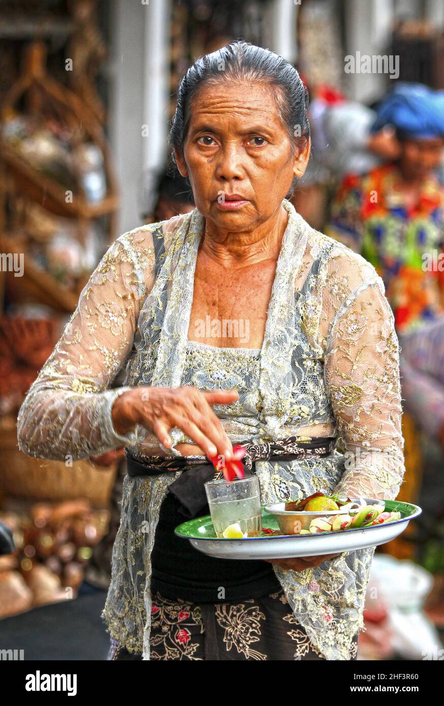 Eine balinesische Frau, die hinduistische Canang Sari-Gaben auf dem Sukawati-Markt in Bali, Indonesien, trägt Stockfoto