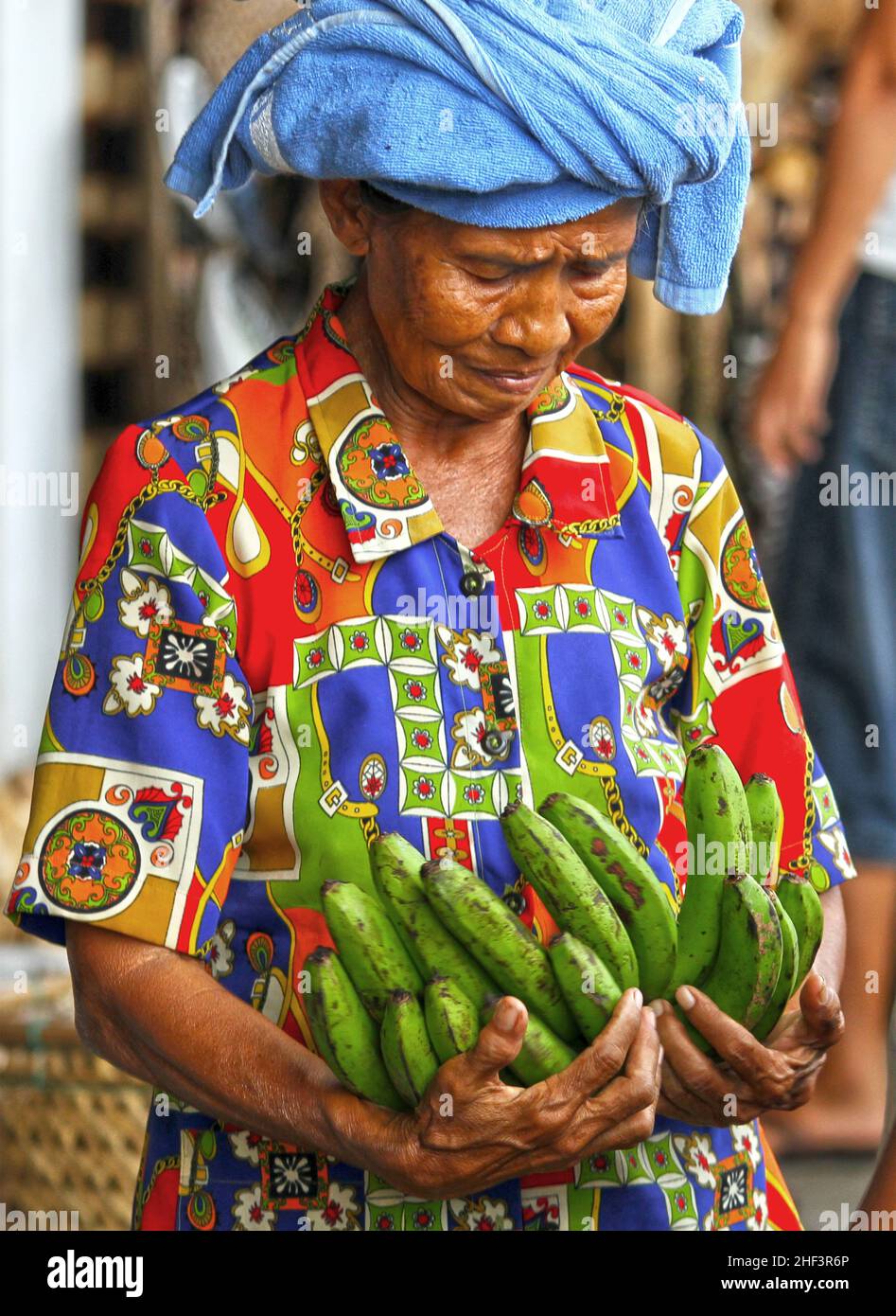 Eine ältere balinesische Frau, die weint, während sie Banansa in ihren Händen auf dem Sukawati Markt in Bali, Indonesien, trug Stockfoto