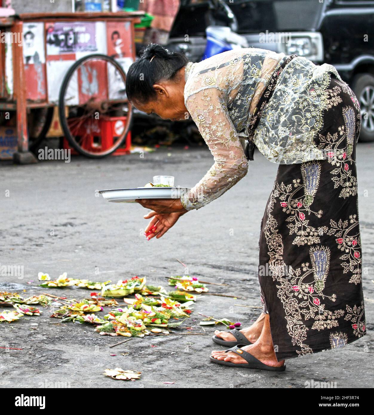 Eine balinesische Frau, die sich beugte, um Opfergaben oder Canang Sari auf dem Sukawati Markt in Bali, Indonesien, zu platzieren Stockfoto
