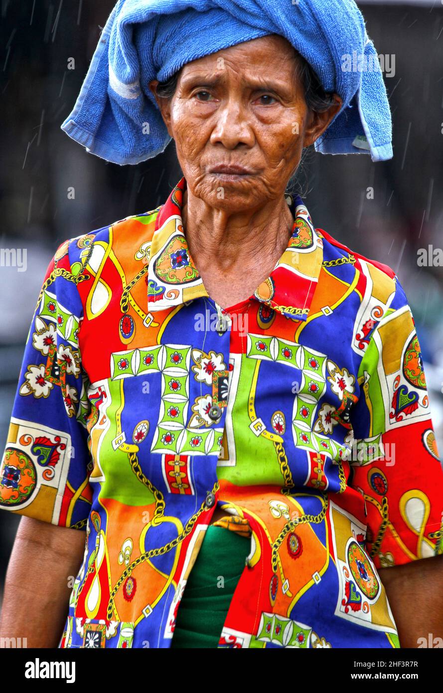 Eine traurig aussehende ältere balinesische Frau mit einer bunten Bluse auf dem Sukawati Markt in Bali, Indonesien Stockfoto