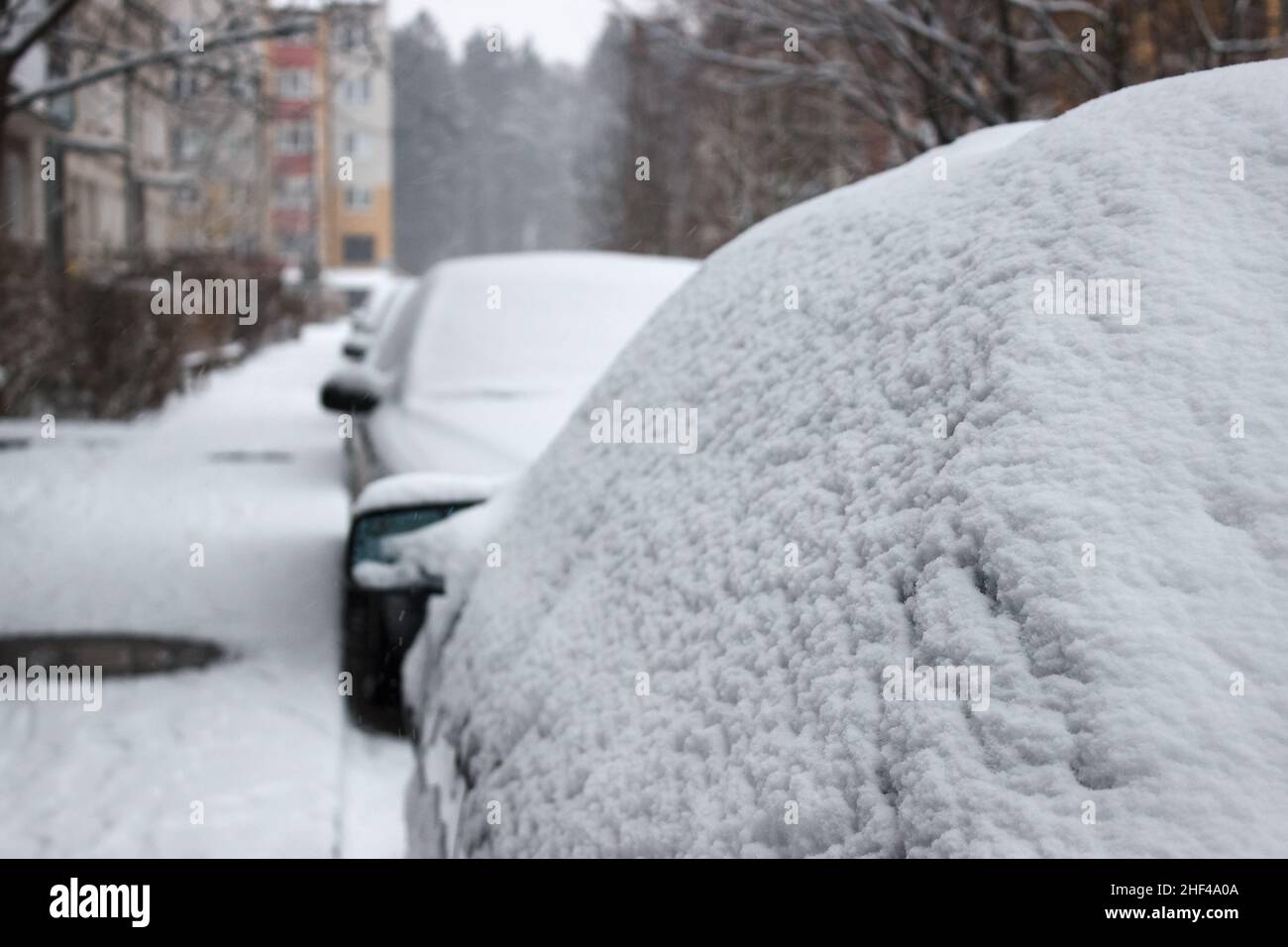 Auto bedeckt mit Schnee am Wintertag auf der Stadtstraße Stockfoto