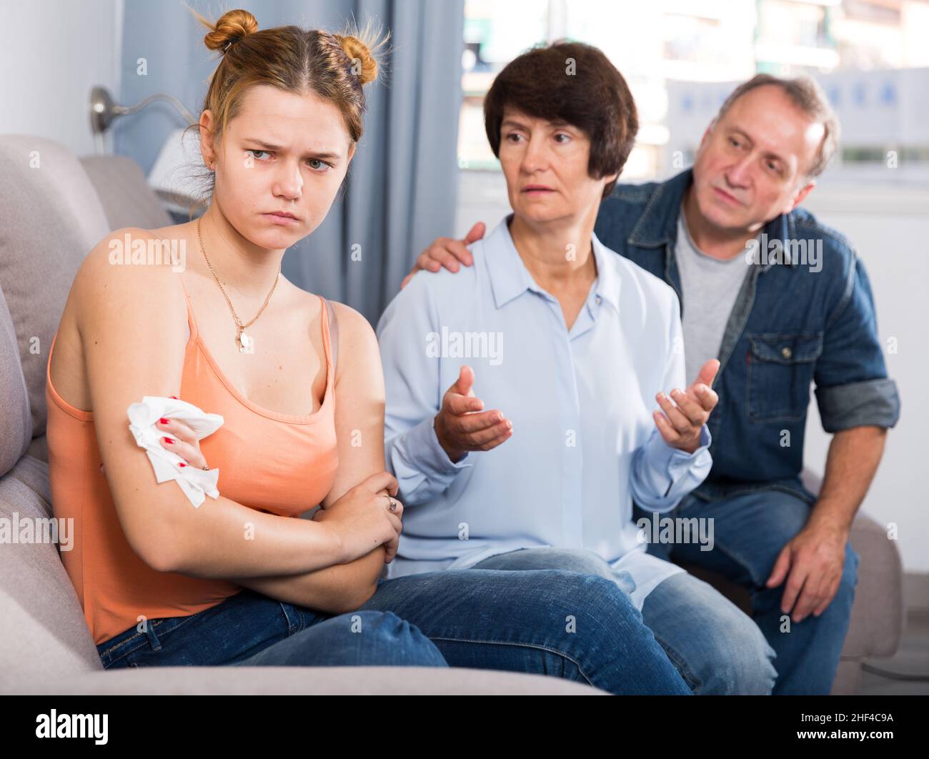 Die Eltern trösten die verärgerte Erwachsene Tochter auf dem Sofa Stockfoto