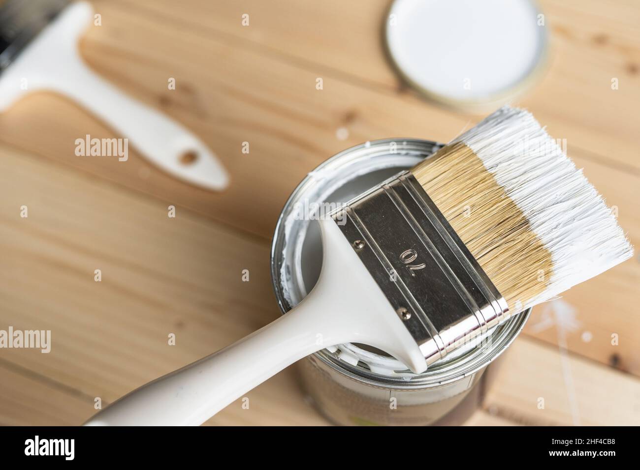 Draufsicht auf weißem Pinsel auf der geöffneten Dose Auf dem Holztisch oder Bodenbemalung und Renovierung Reparatur Konzept Stockfoto