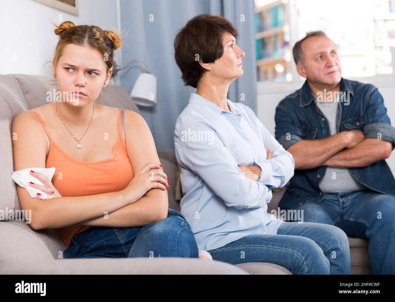 Die Eltern trösten die verärgerte Erwachsene Tochter auf dem Sofa Stockfoto