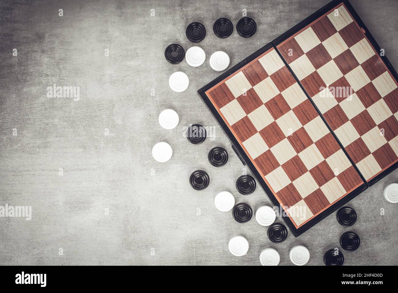 Steine sind in der Nähe des Schachbretts verstreut, Draufsicht. Gedankenspiele, geistige Entwicklung und Strategie. Spiele für Kinder und Erwachsene. Schachschule. Stockfoto