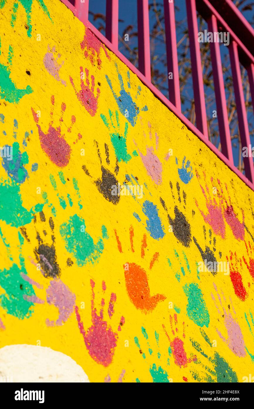 Farbenfrohe Handdrucke an einer leuchtend gelben Wand Stockfoto