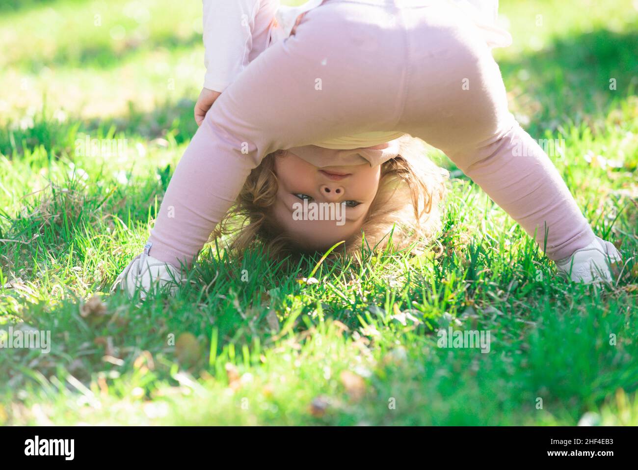 Lifestyle Portrait Baby Mädchen Kind in happines an der Außenseite in der Wiese auf den Kopf. Stockfoto