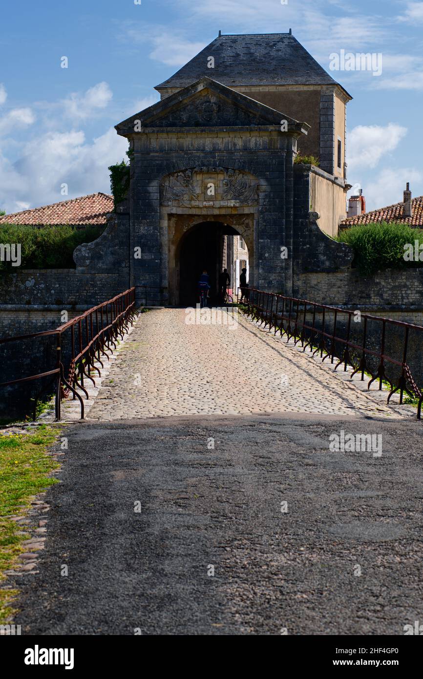 porte des campani in Saint-Martin-de-Ré auf der Ile de Ré an einem sonnigen Tag im Sommer mit Menschen, die auf einem Fahrrad darunter reiten. Stockfoto