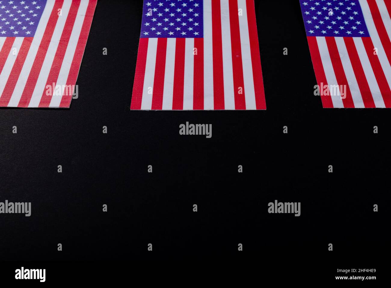 USA-Flaggen mit Sternen und Streifen, die durch einen Kopierraum auf schwarzem Hintergrund abgeflacht sind Stockfoto